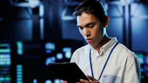 Tech support worker between server room equipment providing processing resources for businesses worldwide. Skillful developer fixes data center supercomputers used for managing massive databases
