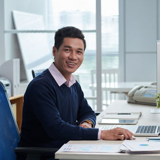 Portrait of smiling Vietnamese businessman sitting at workplace and looking at camera, Portrait of smiling Vietnamese businessman sitting at workplace and looking at camera