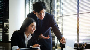 Business people analysing and discussing online data with laptop computer in office.	
