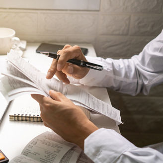 A business man holding pen while looking at the bills in his workplace. Business concept.