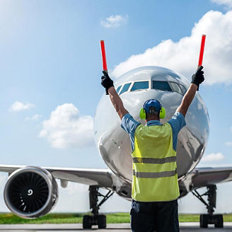 Ground Crew in the signal vest. Aircraft is taxiing to the parking place.