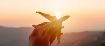 hand holding miniature plane at sunset