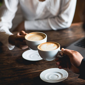 Close-up of a man and woman clinking a white coffee cup in a coffee shop representing domestic business in Budget 2027