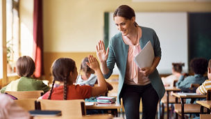 Happy elementary school teacher giving high-five to her student representing income tax in Budget 2027