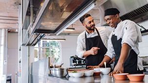 Happy men chefs cooking food at cafe kitchen representing indirect taxes in Budget 2027