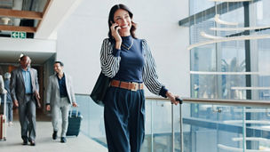 Woman on phone call in airport representing international business in Budget 2027