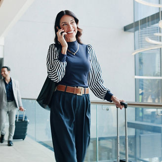 Woman on phone call in airport representing international business in Budget 2027