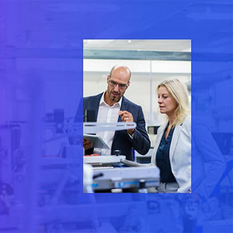 Two people in factory lab looking at machinery