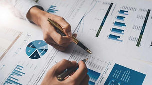Hands pointing pens at charts representing financial services