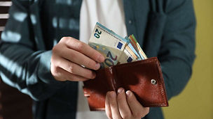 Person counting euros in wallet representing income tax