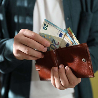 Person counting euros in wallet representing income tax