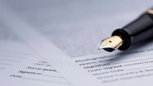 Fountain pen lying on scattered legal contract documents on table, shot with very shallow depth of field