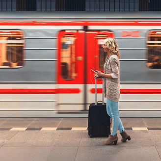 Woman in train station with train in motion