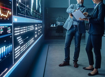 Project Manager and Computer Science Engineer Talk while Using Big Screen Display and a Laptop
