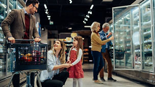 Cheerful family with one girl shopping groceries in supermarket