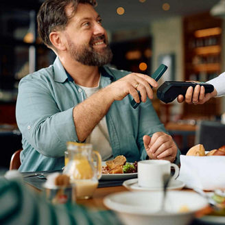 Close up of man using smartphone while paying to a waitress in a restaurant.