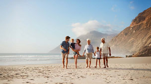 Multi-generational family walking on beach, private client services