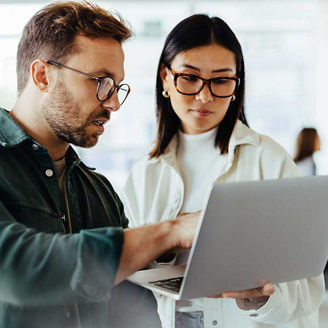 Two people looking at laptop in office representing provision 29 of the UK corporate governance code