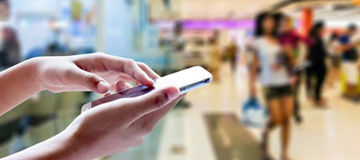 Hand holding smartphone in shop