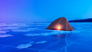 Illuminated tent on iced over Zeya river in Russia