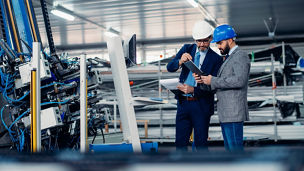 Engineers talking while inspecting machinery stock photo. Shadow DOF. Developed from RAW; retouched with special care and attention; Small amount of grain added for best final impression. 16 bit Adobe RGB color profile.