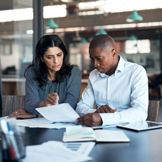 Fotografía de un hombre y una mujer revisando unos papeles sentados en una oficina