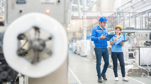 The European male engineer and the Asian female engineer, stationed in the industrial sector, oversee machinery, ensuring top-notch production standards for global market competitiveness.