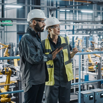 Male Specialist and Female Car Factory Engineer in High Visibility Vests Using Tablet Computer. Automotive Industrial Manufacturing Facility Working on Vehicle Production. Diversity on Assembly Plant.