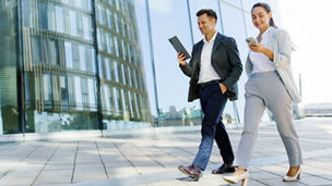  man and woman walking looking at their phones
