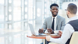 Portrait of successful African-American businessman smiling during meeting with colleague at coffee break