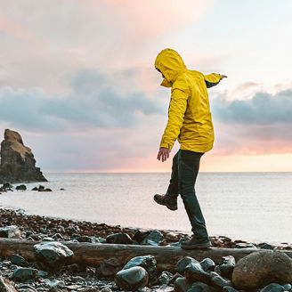 Man hanging in the balance over a log at seaside in Scotland - Hiker having fun at beautiful destination Talisker bay after the rain - Filter applied, travel and adventure concepts