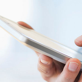 Hand holding digital tablet over stack of books