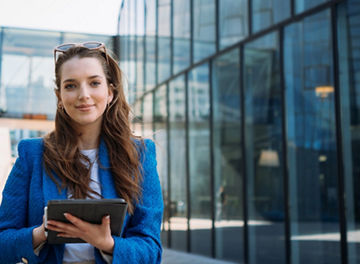 Successful woman real estate agent holding tablet and looking to camera. Business centre location. High quality photo