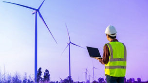 Man with laptop near electric windmills