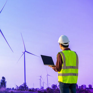 Man with laptop near electric windmills