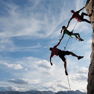hikers helping each other climb