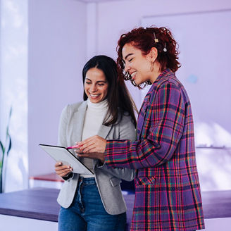 two woman smiling at a ipad