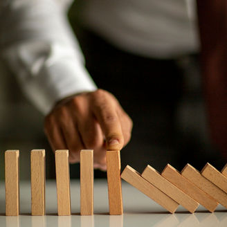 Hand stopping a row of falling wooden blocks