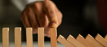 Hand stopping a row of falling wooden blocks