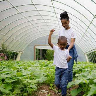 A woman and a young boy walking through a greenhouse