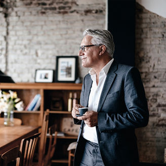 Japanese alt text: ティーカップを持ち微笑む男性