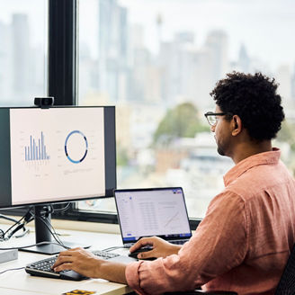 Businessman analyzing sales graph on computer screen at office. Entrepreneur is preparing finance data. He is using keyboard and mouse.