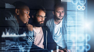 Three people are working in front of a monitor