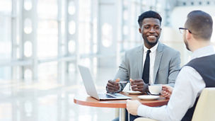 Portrait of successful African-American businessman smiling during meeting with colleague at coffee break