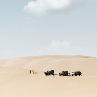 ナミブ砂漠をゆく3台の車とひと