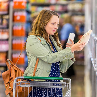 片手にスマートフォンを持ちながら買い物をする若い女性