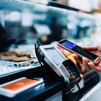 Close up of a woman's hand paying with her smartphone in a cafe, scan and pay a bill on a card machine making a quick and easy contactless payment. NFC technology, tap and go concept
