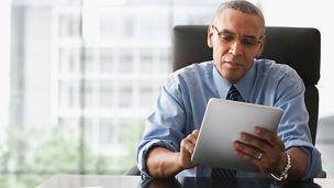 席にかけてタブレットを見るビジネスパーソン