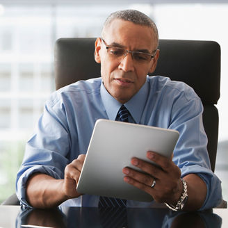 席にかけてタブレットを見るビジネスパーソン