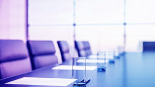Close up of conference room with glasses of water on the table with papers, armchairs and a large window. 